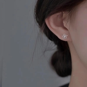 Close-up of minimalist S925 sterling silver hollow flower stud earrings worn by a model