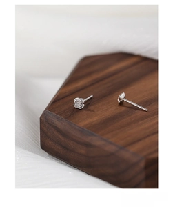 Macro shot of S999 sterling silver rose stud earring with certified hallmark on walnut base