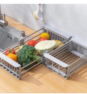 Close-up of extendable stainless steel sink rack holding fresh vegetables and broccoli