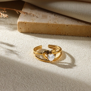 Detailed view of irregular golden ring with heart-shaped transparent gemstone on beige fabric