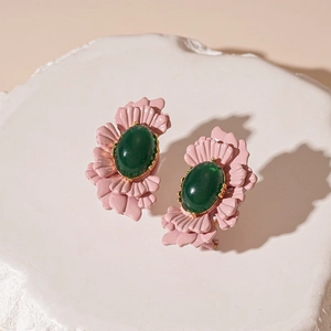 Macro detail of vintage pink petal earrings with oval green resin stone center