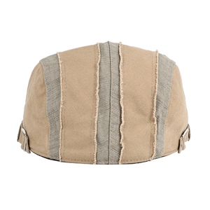 Detail of khaki and grey patchwork newsboy hat with side metal buckle and raw seams