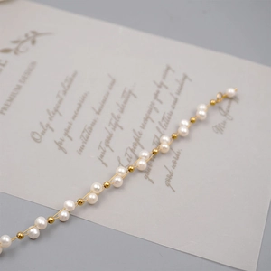 Elegant gold bead and white freshwater pearl bracelet on vintage paper background