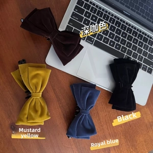 Flat lay of velvet bow hair claws in dark coffee, mustard yellow, royal blue and black