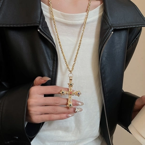 Retro cross pendant necklace with colorful gemstones worn over a stylish black leather jacket