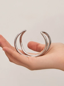 Dettaglio di un bracciale rigido aperto a doppio strato minimalista con finitura argento