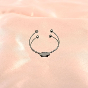 Detailed view of silver stainless steel double-layered open bangle with central cabochon tray