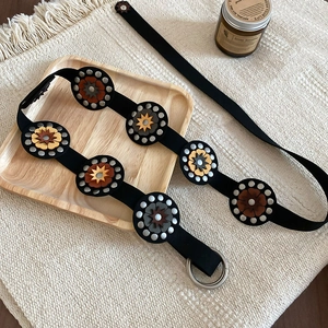 Detail of vintage bohemian black waist belt with floral patches and silver metal ring buckle