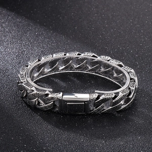Close-up of vintage silver Cuban chain bracelet with black Greek key pattern engraving