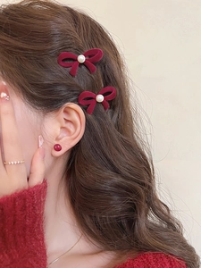 Close-up of burgundy velvet bow hair clip with pearl and matching round stud earrings