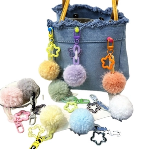 Colorful plush flower ball keychain with star acrylic chain on a blue denim bag