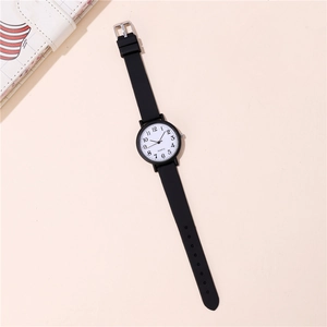 Primer plano de un reloj de cuarzo minimalista con correa de silicona negra y esfera blanca