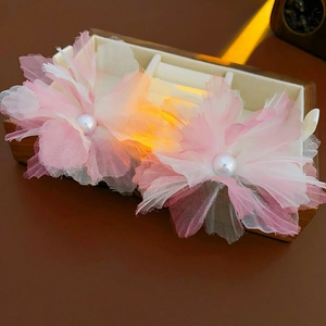 Detail of pink mesh flower hair clips with pearls in a wooden jewelry display case