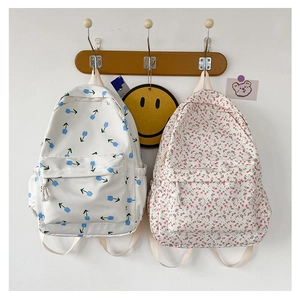 Floral canvas backpacks featuring blue tulip and pink flower patterns on wooden hooks