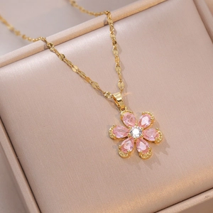 Macro shot of gold flower pendant necklace with pink and white stones on jewelry box