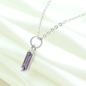 Macro shot of purple rectangular zircon pendant on fine silver chain with elegant fabric background