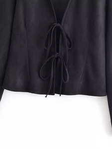 Detail of black long sleeve lace-up top with textured matte suede fabric and front bow