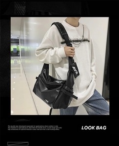 Detail of crossbody bag featuring wide shoulder strap with a detachable small logo pouch
