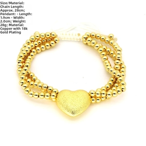 Dettaglio di un bracciale a tre strati di perline placcato oro 18k con ciondolo a cuore