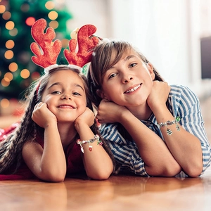 Two young girls wearing festive Christmas bead bracelets with Santa and snowman charms