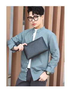 Close-up of black woven leather clutch bag with wrist strap held by male model