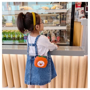Close-up of a child wearing a cute orange fruit-shaped mini crossbody bag with a metal chain