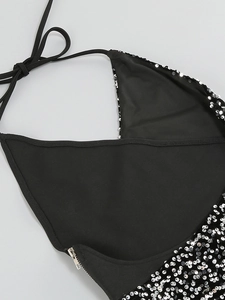 Macro detail of silver sequins on black dress with metallic zipper and halter strap