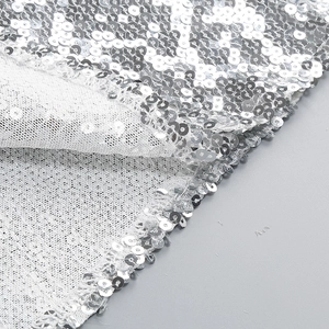 Detailed close-up of sparkling silver sequins stitched on premium white mesh fabric