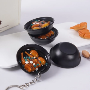 Miniatur-Hühnersuppen-Schlüsselanhänger aus Harz mit Metallring auf weißem Teller