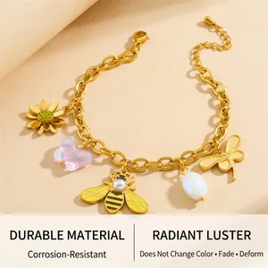Detail of gold-plated charm bracelet with bee, flower, and butterfly on a natural background