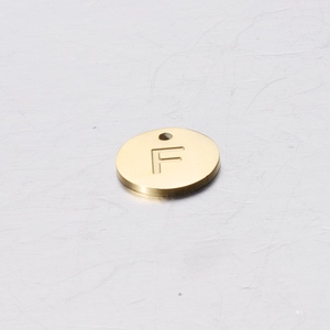 Detailed close-up of 12mm golden stainless steel round pendant with engraved letter F
