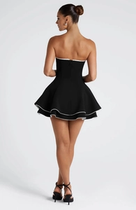 Detail of a back view showing a strapless black dress with white layered ruffles and zipper