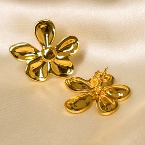 Golden five-petal flower stud earrings with metallic center on silk fabric