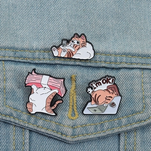 Three cute cartoon enamel cat brooches featuring working and resting orange cats on denim