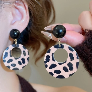 Close-up of pink leopard print circular earrings with black ball studs and gold rings
