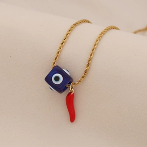 Detail of gold twisted chain necklace with blue evil eye bead and red chili pendant