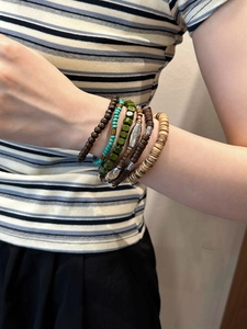 Détail de bracelets bohèmes en perles de bois avec breloques vintage et accents turquoise