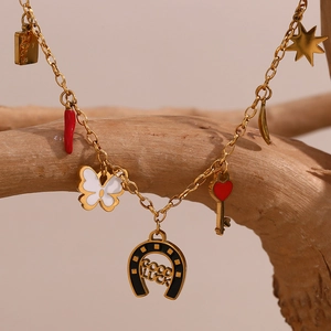 Detalle de collar dorado con múltiples colgantes de mariposa y herradura en rama