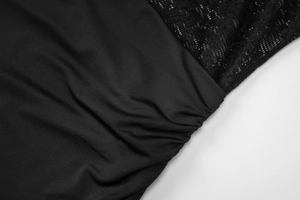 Detail eines schwarzen Kleides mit Spitzen-Patchwork und geraffter Stoffstruktur