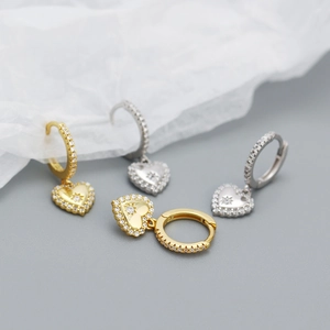 Macro shot of heart-shaped earrings with fine pavé crystals in gold and silver finish