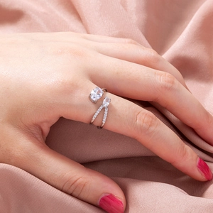 Close-up of adjustable silver ring with zircon stones on pink silk fabric background