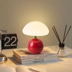 Minimalist red ceramic mushroom desk lamp on books creating a warm cozy atmosphere