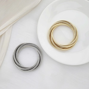 Multilayer wrap spring bracelets in gold and silver finish on a ceramic plate