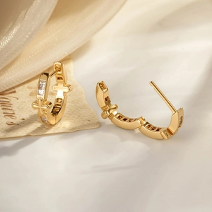 Vintage gold cross hoop earrings with clear cubic zirconia on elegant beige fabric
