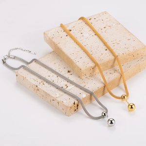 Gold and silver stainless steel ball pendant necklaces displayed on textured stone
