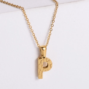 Macro shot of 18K gold plated letter P pendant with a unique stone texture and link chain
