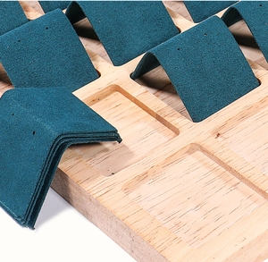 Detailed close-up of dark green velvet slots in a wooden jewelry display tray