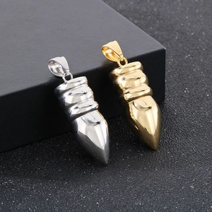 Close-up of bullet-shaped gold and silver pendants in stainless steel on dark box