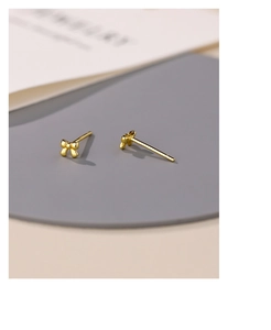 Macro shot of gold bow stud earrings showing the S925 sterling silver certification mark