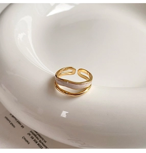 Detail of a gold double-layered adjustable ring with white pearlescent inlay on a ceramic rim